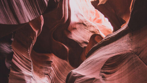 Red rock canyon with smooth sandstone walls and glowing light from above.