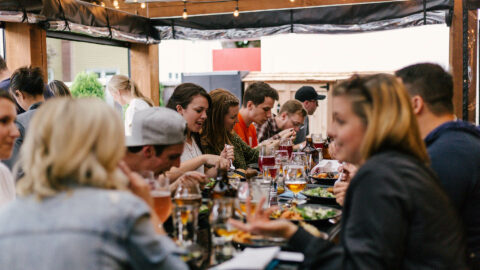 Friends eating at large table at outdoor restaurant.