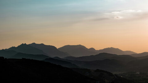 Distant mountain peaks lit by soft sunrise light.